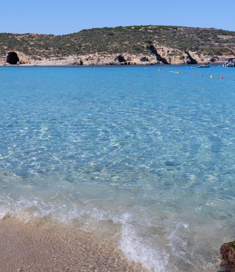 Turquoise water of the Blue Lagoon on Comino with boats anchored nearby.