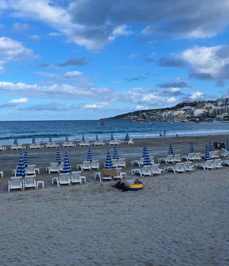 Wide sandy Mellieha Bay with calm blue water.